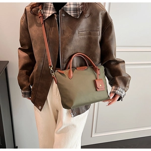 Olive green nylon tote bag with brown leather handles worn by a model in a casual outfit