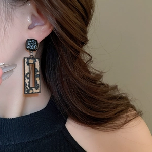 Gros plan de boucles d'oreilles géométriques léopard avec texture noire martelée