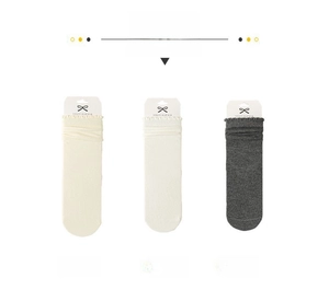 Dettaglio della maglia e polsini con volant di calze nei colori crema, bianco e grigio