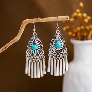 Detail of vintage bohemian dangle earrings with turquoise stones and silver metal tassels