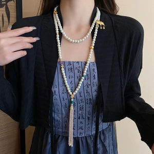 Detail of layered pearl necklace with gold plated lotus charms and tassels on model