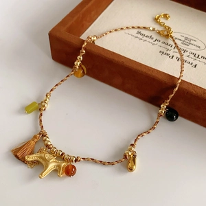 Detail of woven horse pendant necklace with golden elephant and brown tassel
