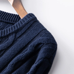 Detailed view of navy blue cable-knit sweater collar on a premium wooden hanger