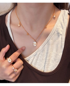 Détail du collier plaqué or 18K avec nacre ovale et pendentifs étoiles sur le mannequin