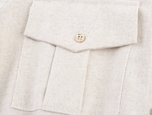 Détail du tissu beige en coton et lin et de la poche à rabat avec son bouton