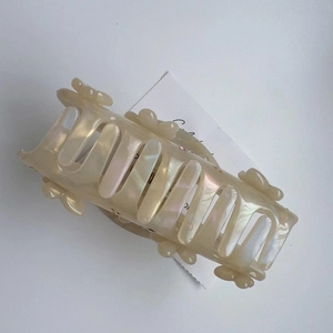 Vue détaillée d'une pince à cheveux en acétate beige nacré avec papillon strass