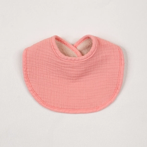 Detail of pink cotton baby bib featuring absorbent crinkled muslin fabric and soft edges