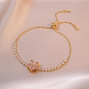Elegant gold bracelet with pink flower pendant and sparkling zircons on silk background
