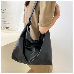 Detail of black matte faux leather tote bag with unique knotted shoulder strap decor