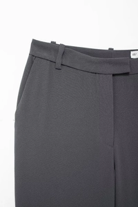 Close-up detail of high-waist dark grey dress pants with belt loops and side pockets
