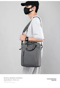 Close-up of a charcoal grey nylon crossbody bag with orange logo and wide shoulder strap