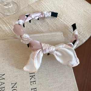 Dettaglio di un cerchietto in tessuto floreale rosa e bianco con fiocco e dentini