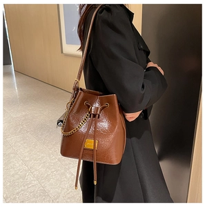 Détail du sac seau marron vintage avec chaîne dorée et texture cuir ciré effet froissé