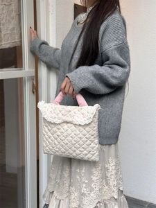 Detailed macro view of cream quilted cotton laptop bag with pink handles and lace trim