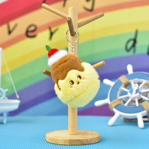 Macro detail of a cute yellow plush croissant character keychain hanging on wooden stand