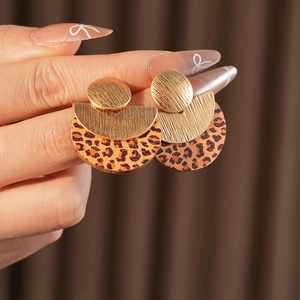 Detailed close-up of geometric gold metal earrings with leopard print accents