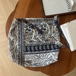 Detailed top view of a large bohemian paisley print cotton linen crossbody bag on a table