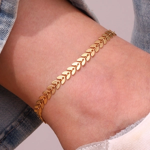 Detail of 18K gold-plated stainless steel anklet featuring delicate leaf charms on skin
