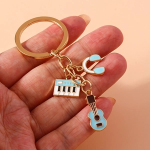 Musical instrument keychain with blue guitar and piano keyboard pendants held in hand