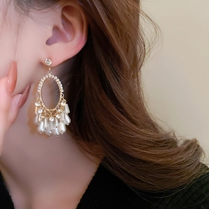 Close-up of elegant gold vintage earrings with pearls and crystals on a female model