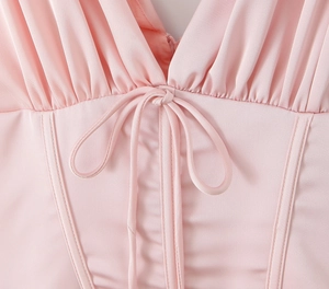Détail de la robe rose avec décolleté en V plongeant, cordon de serrage et plissés