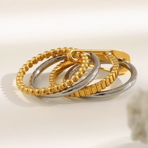 Detail of stacked two-tone stainless steel rings with a gold safety pin accent