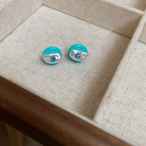 Detailed macro view of round turquoise resin earrings with silver accents and blue crystals