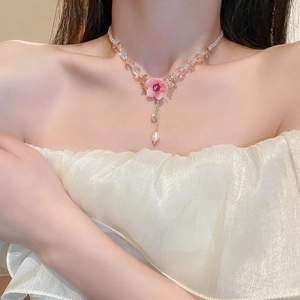 Detail of pink flower pendant necklace with champagne beads and pearl fringe on a model