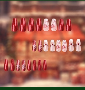 Detail of coffin-shaped nails featuring red glitter, white snowflakes, and rhinestones
