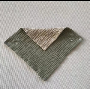 Close-up of double-layer muslin cotton baby bib with olive green and animal print sides