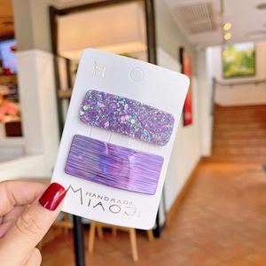 Detail of purple iridescent and glitter hair clips on a handmade brand display card