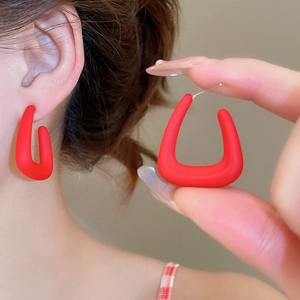 Close-up of stylish matte wine red U-shaped acrylic earrings with a smooth finish