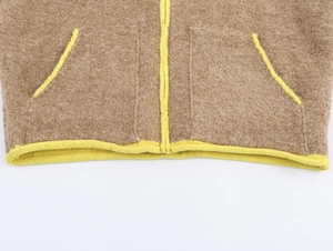 Dettaglio del gilet in pile marrone con bordi gialli vivaci e orlo con zip