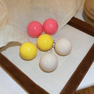 Close-up of candy colored ball stud earrings set in pink, yellow and white resin finish