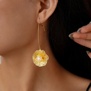 Close-up of 18K gold plated floral drop earrings with sparkling zircon on model's ear