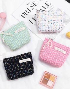Macro shot of tweed cosmetic bags with pearl pendants and elegant brand label detailing