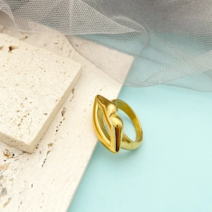 Detailed view of 14K gold hollow lip-shaped ring on beige travertine stone with mesh