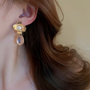 Close-up of vintage flower earrings with pearl studs and purple oval resin charms