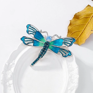 Macro detail of dragonfly brooch with blue rhinestones and gradient enamel inlay