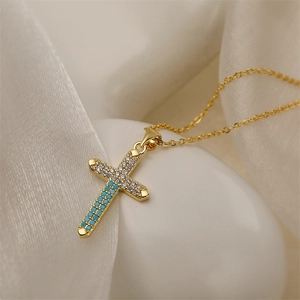 Detail of gold cross necklace with turquoise and cubic zirconia on white silk fabric