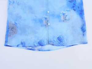 Dettaglio del tessuto in chiffon blu a fiori con trama fine e bottoni bianchi