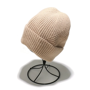 Detailed view of beige ribbed knit beanie texture and thick fold-up cuff on a stand