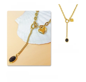 Macro detail of golden heart necklace with black oval gemstone and OT buckle chain