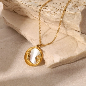 Detailed close-up of a gold star and moon pendant with mother of pearl inlay on a rock