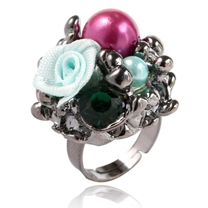 Détail d'une bague rose et perle avec fleur en tissu bleu et sertie d'une pierre verte