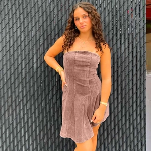 Détail de la mini-robe en jean marron sans bretelles avec coutures et coupe ajustée
