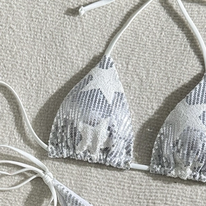 Detailed macro view of white sequined bikini top featuring shimmering silver star-like sequins