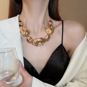 Close-up of a model wearing a gold abstract necklace with irregular pleated metal links