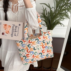 Detail view of colorful geometric quilted tote bag with floral patterns and logo patch