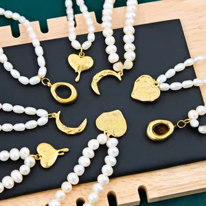 Macro shot of gold crescent and heart pendants with vintage textures on pearl necklaces
